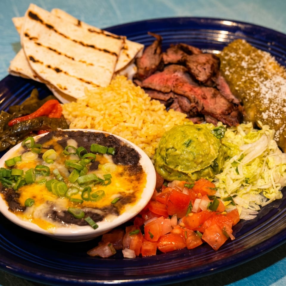 Mexican platter with grilled steak, rice, beans, tortillas, guacamole, salsa, vegetables, and melted cheese dip.